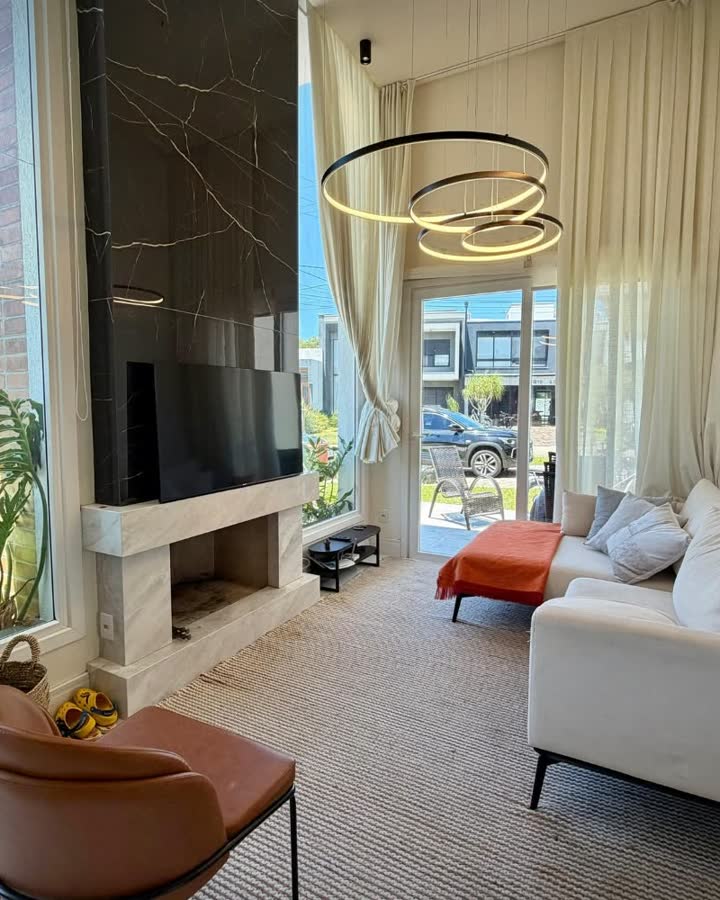 Sala com pé-direito alto, lareira e porta de vidro