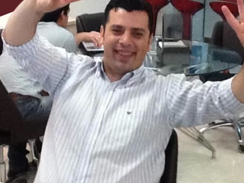 Adriano em 2011, sorrindo e fazendo sinal de vitória num escritório